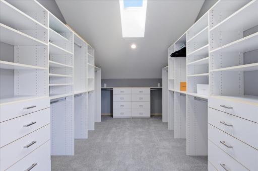 Walk-in closet with custom organization system, built-in drawers, and skylight.