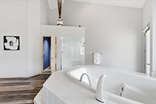 Alternate view of the primary bathroom showing the soaking tub and private toilet.