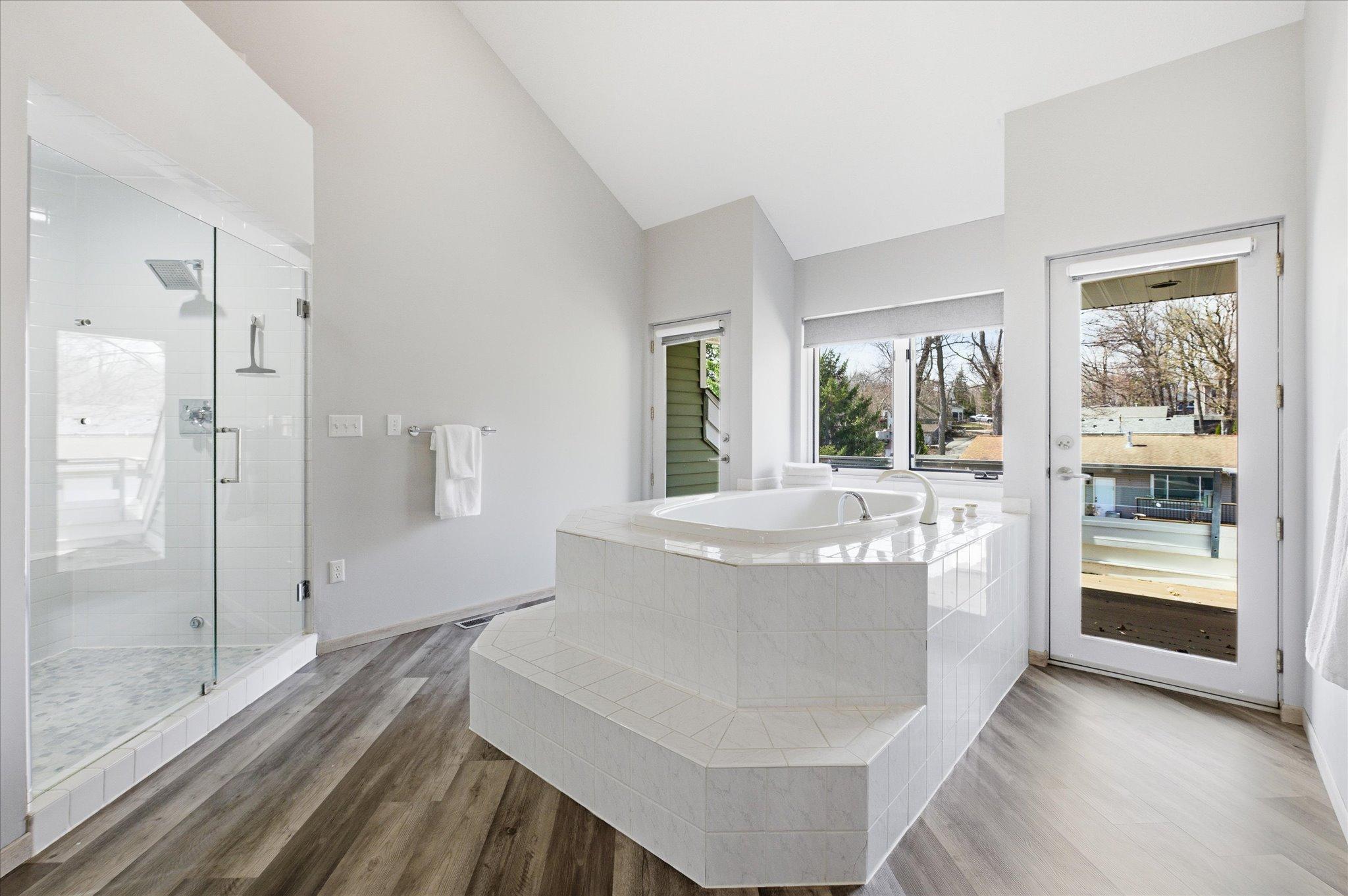 Primary bathroom with soaking tub, walk-in shower, and access to the private sunbath deck.