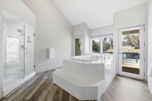 Primary bathroom with soaking tub, walk-in shower, and access to the private sunbath deck.
