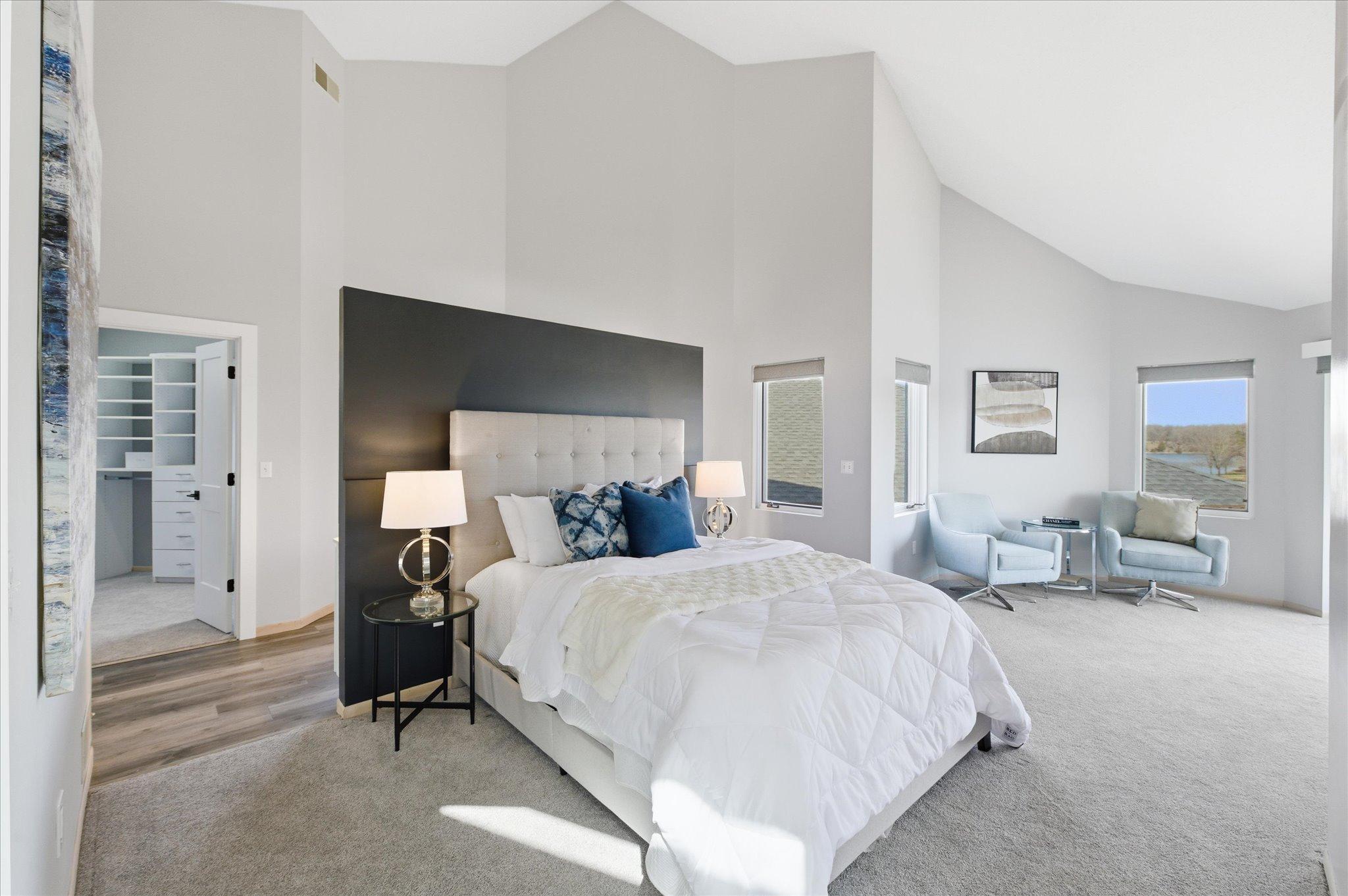 Primary bedroom with vaulted ceiling, sitting area, and access to a private deck overlooking the lake.