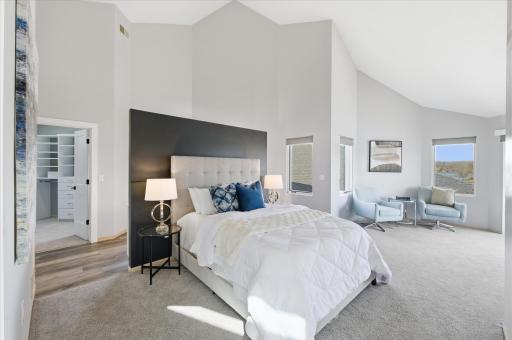 Primary bedroom with vaulted ceiling, sitting area, and access to a private deck overlooking the lake.