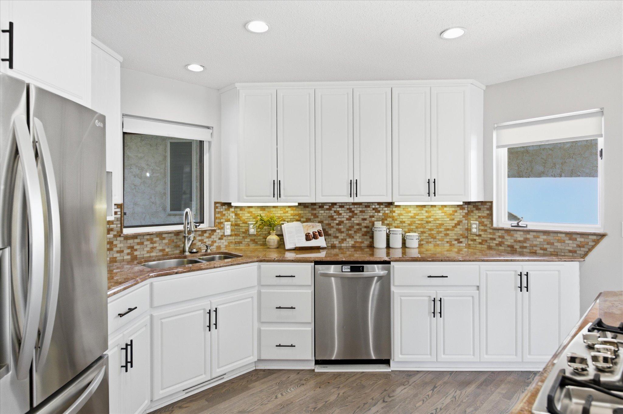 Kitchen workspace with under-cabinet lighting, stainless steel dishwasher, and double sink.