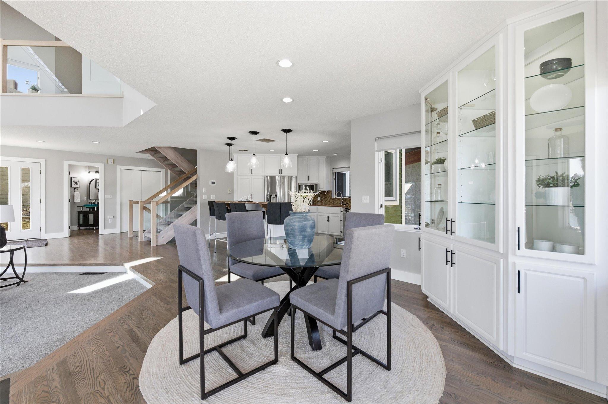View of the dining area looking toward the kitchen, staircase, and built-in display cabinetry.