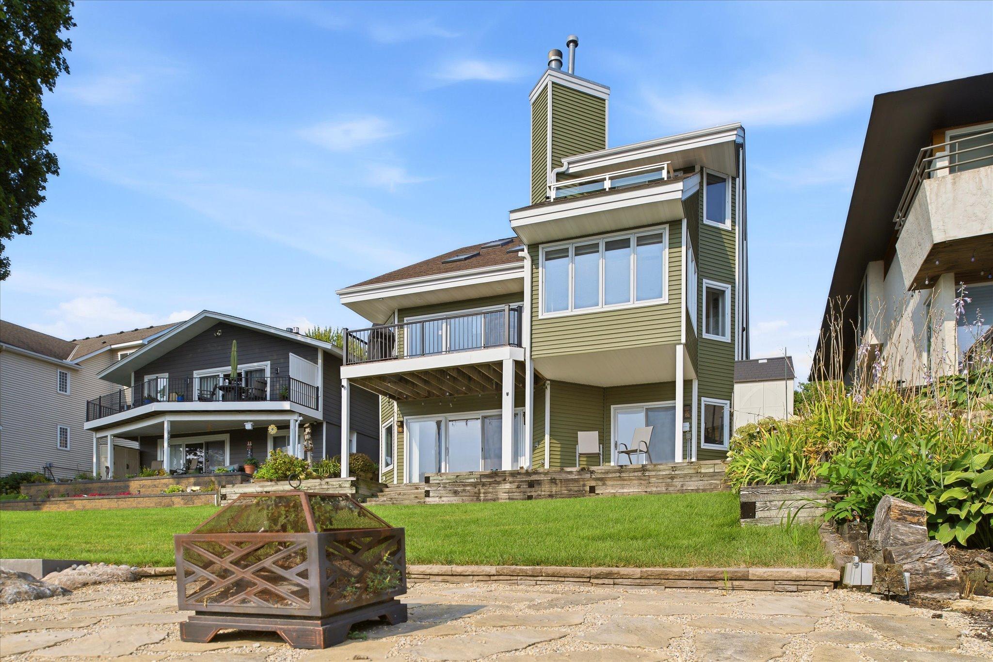 Lakeside exterior with lawn, patio area and elevated deck overlooking the water.
