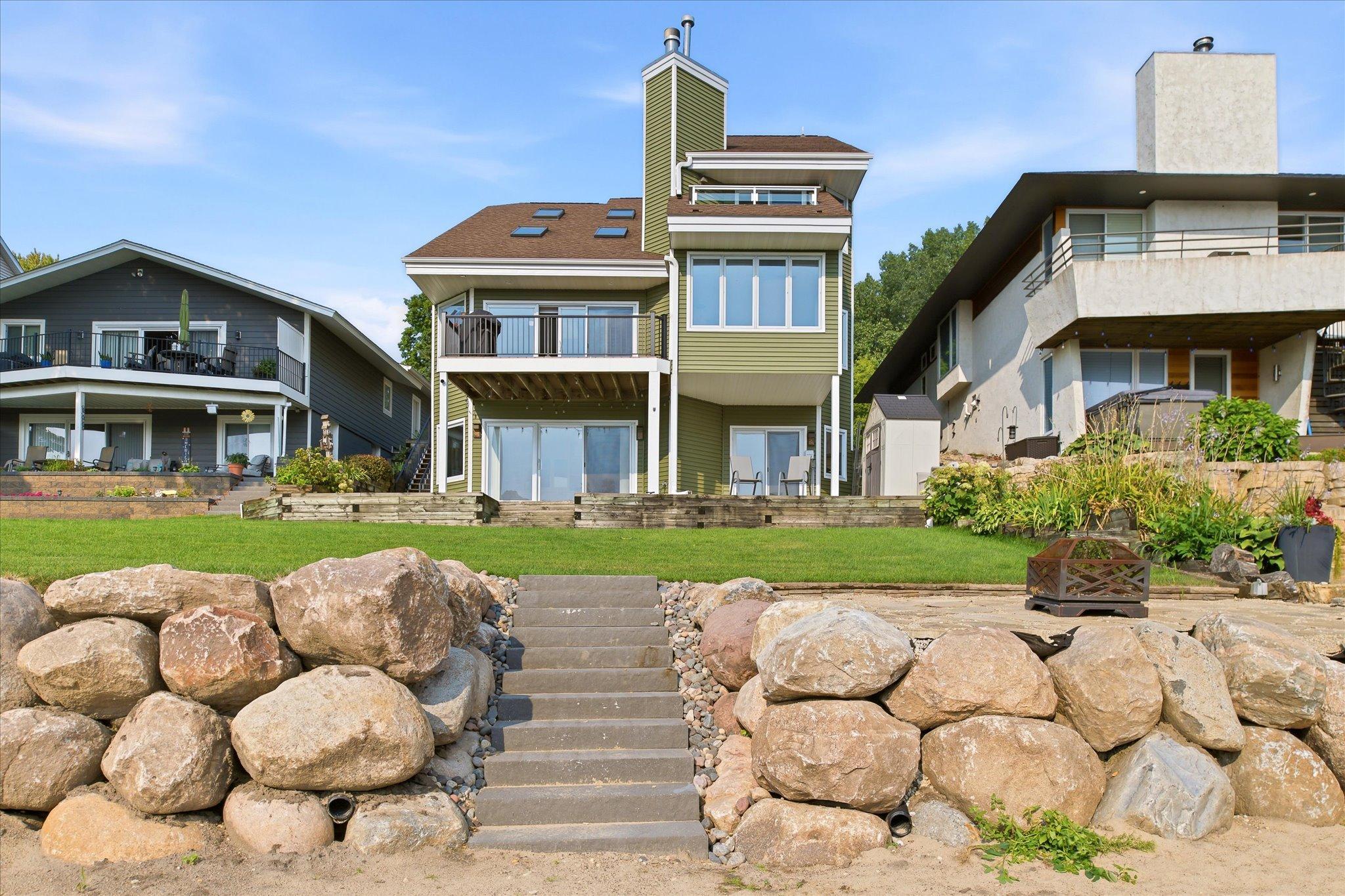 Rear lakeside exterior showcasing the home, elevated deck and newly installed deck railings.