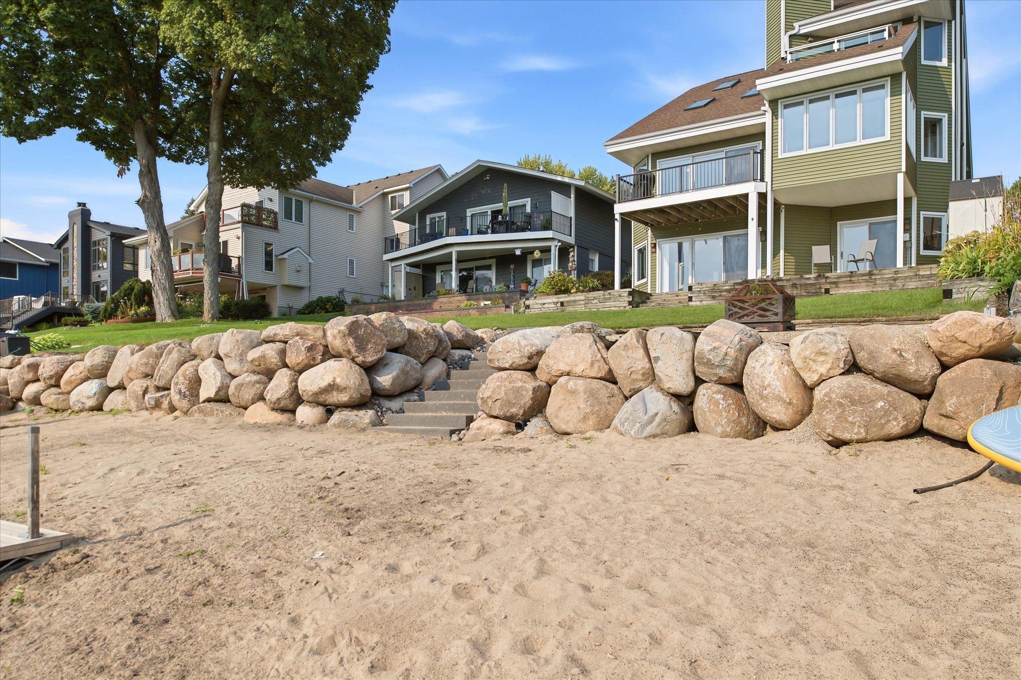 Lakeside exterior featuring a level lawn, boulder retaining wall and steps to the shoreline.