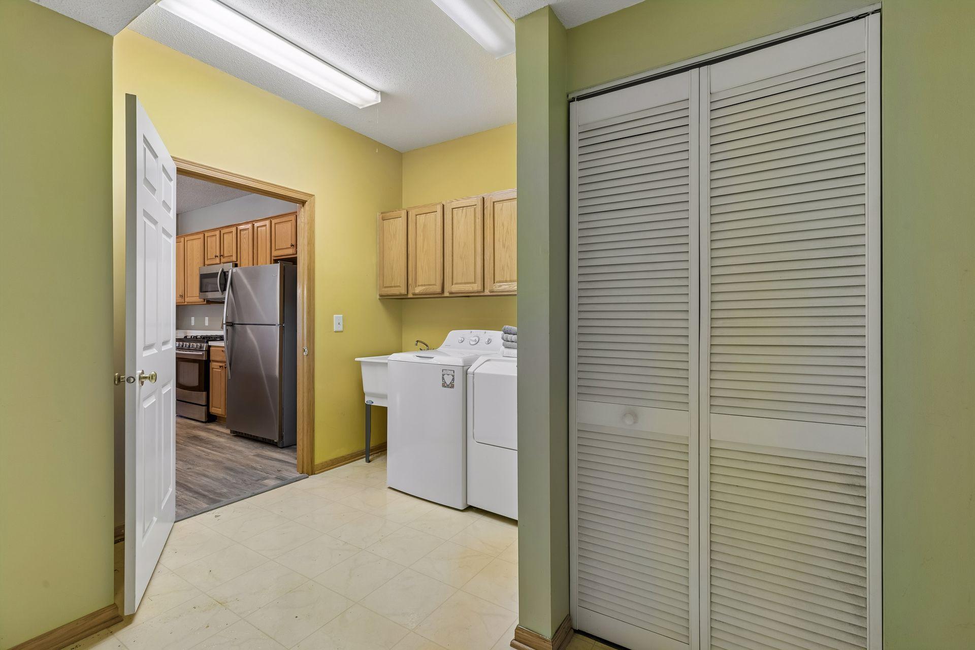 Here is the laundry room with upper cupboards and a utility sink. The shuttered door houses the HVAC components and this room has good finished storage space.