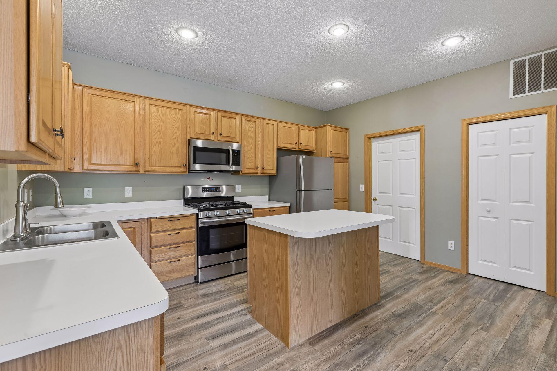 LVP flooring, recessed lights, and a pantry which is behind the white door on the right.