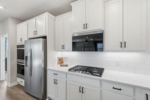 UPGRADED Signature Kitchen with double ovens, gas range, large island with walk-in pantry, quartz countertops and soft close cabinetry. *Photo of similar home with same floor plan