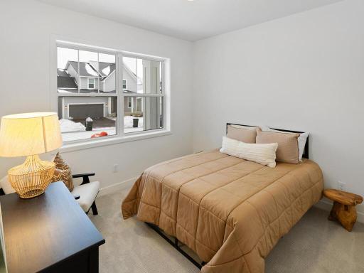 Comfortable second bedroom with a large window providing abundant natural light. Photo shown is from a previously built home; selections and finishes may vary.