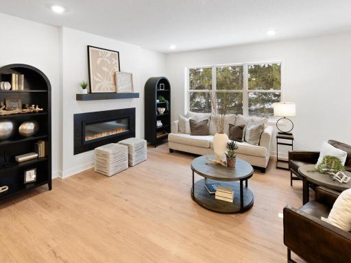 Spacious great room with abundant natural light and a cozy fireplace focal point. Photo shown is from a previously built home; selections and finishes may vary.