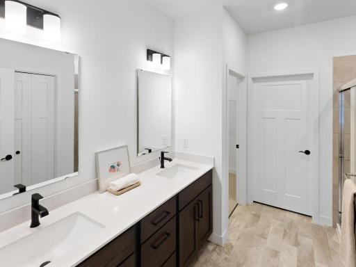 Private primary bath features a double-sink vanity with generous countertop and storage space. Photo shown is from a previously built home; selections and finishes may vary.