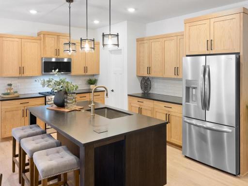 Spacious kitchen features a large center island, abundant cabinetry and stainless steel appliances. Photo shown is from a previously built home; selections and finishes may vary.