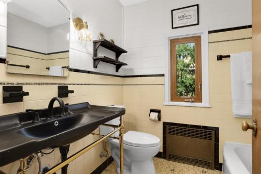 Main floor bathroom with the beautiful original vintage tile, Updated vanity, lights and new toilet.