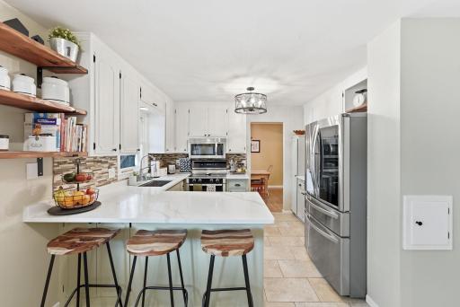Sleek quartz counter tops, custom back splash, and stainless appliances