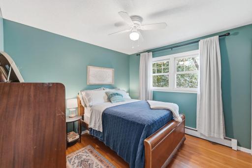 Natural wood flooring and abundant light give this bedroom a warm, comfortable feel.
