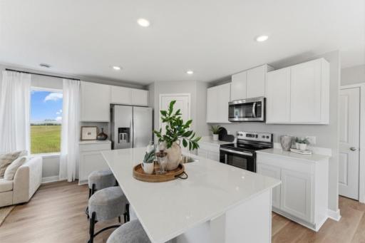 The kitchen features a large island with breakfast bar. Color and options may differ.