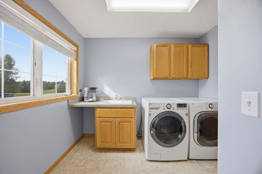 Main floor laundry with extra cabinet space and a laundry sink is light and bright!