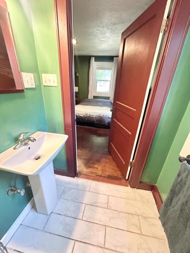 View of full bath looking into the primary suite.