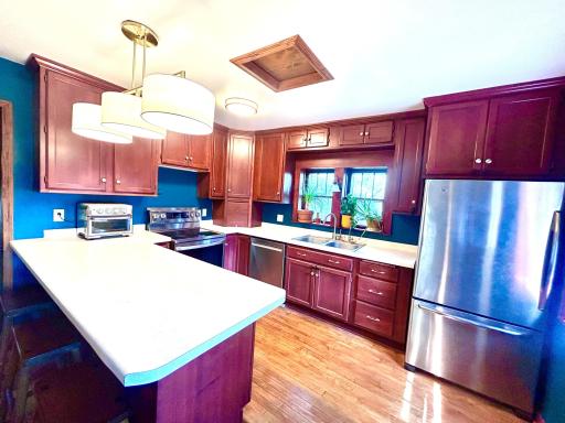 View of well planned kitchen with stainless appliances, cherry cabinets and a large work area also to be used as a snack bar area.