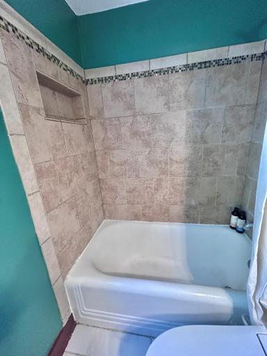 Tiled shower/tub in primary bedroom ensuite.