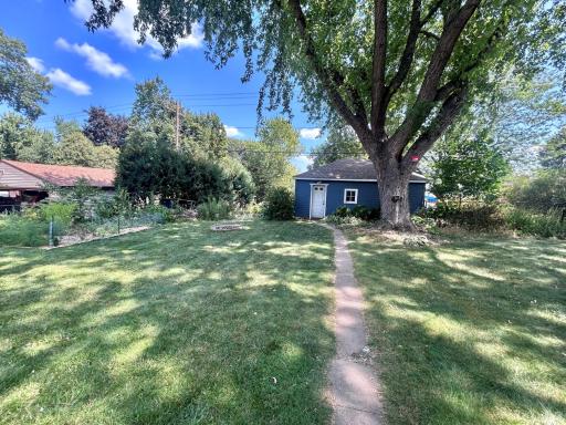 Sidewalk from house to garage service door. Two gardens are located on the left side of this picture.