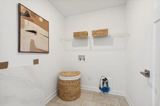Convenient main-level laundry room offers generous cabinetry and countertop space for storage, sorting, and everyday organization.