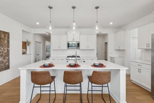 An expansive island anchors the kitchen, offering seating for three and plenty of room for entertaining. Stylish pendant lighting adds a polished finishing touch.