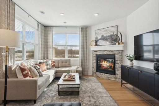 Inviting Great Room with a beautiful stone-surround gas fireplace, abundant windows, and peaceful views—a comfortable gathering space in every season.