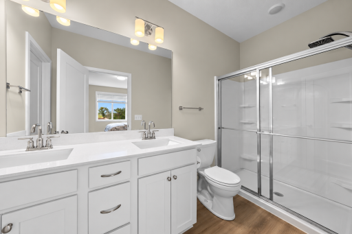 Private primary bath featuring double-sink vanity, large mirror and walk-in shower.