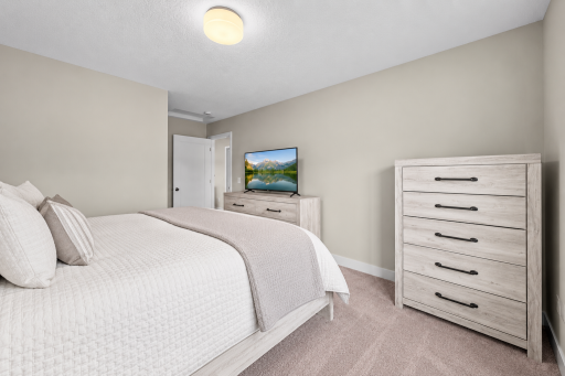 Upper bedroom with neutral finishes, carpeting, large walk-in closet and large window.