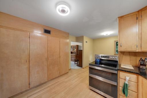 Full wall of storage as wood floors extend into separate eating area.