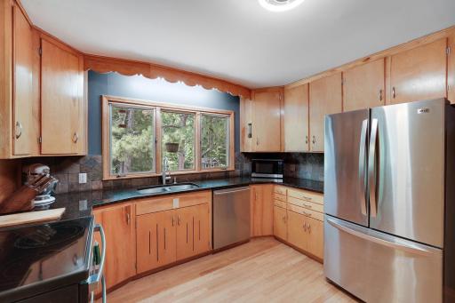 Four walls of cabinets in kitchen with wood floors and stainless steel appliances.