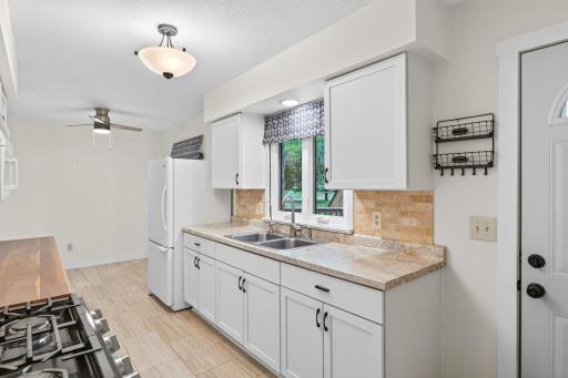 Kitchen has a lovely travertine backsplash with a view of the deck from the kitchen window.