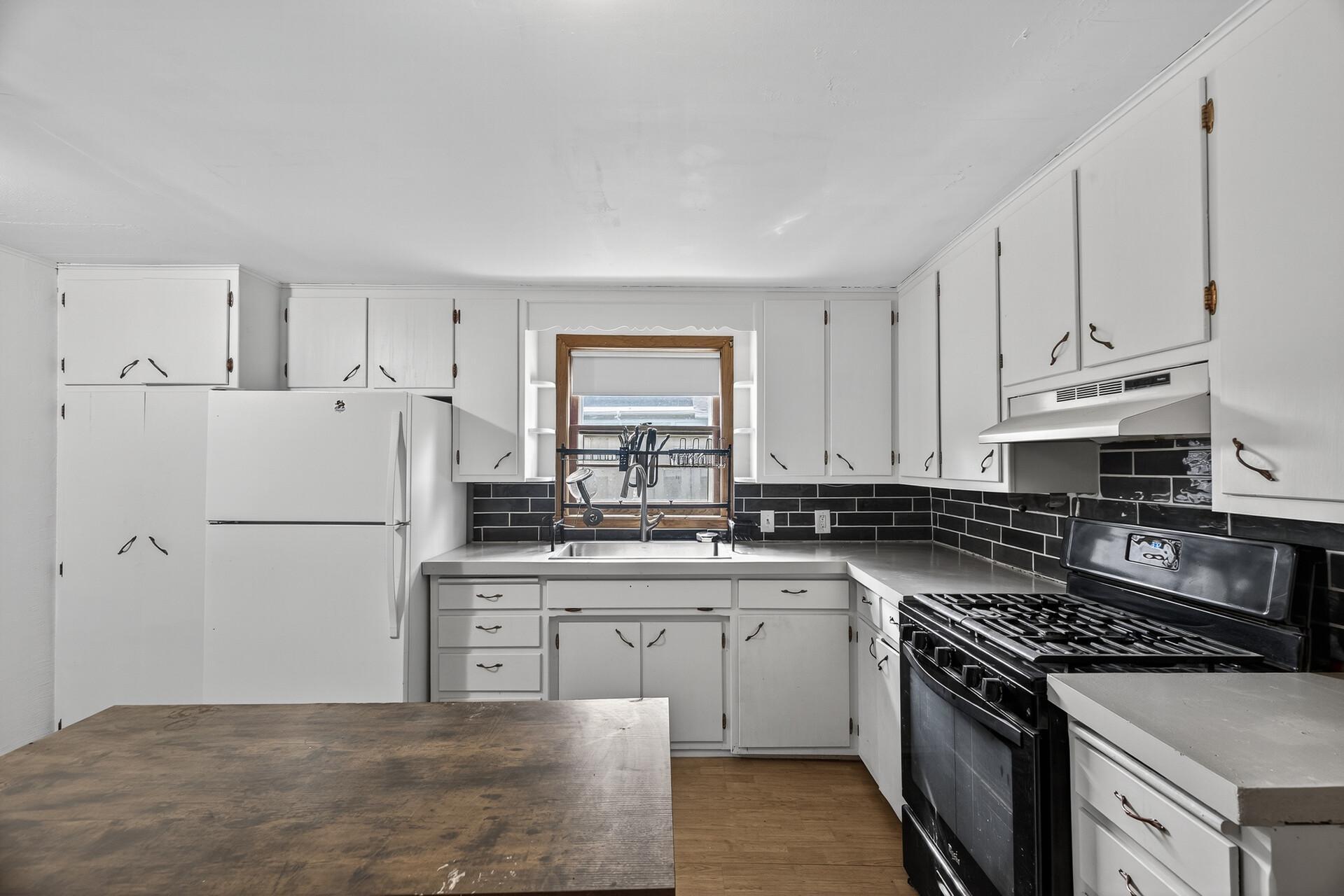 Freshly painted kitchen cabinetry, new concrete countertops and backsplash, sink, faucet and garbage disposal