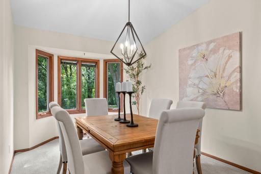 The formal dining room is also accessible from the living room and features a large rear-facing bay window, carpeting, and a modern light fixture.
