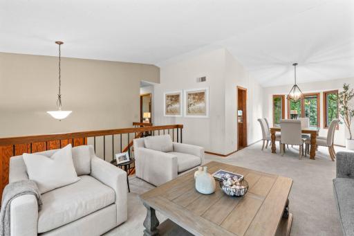 A different view of the living room showcasing views of the nearby dining room and stairs leading down to the front entry.
