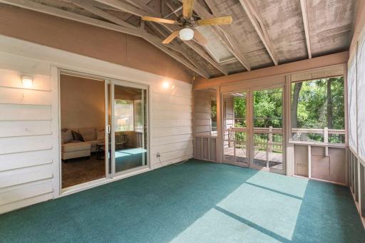 The screened-in three-season porch features a ceiling fan, creating the perfect spot to enjoy the seasons while offering convenient access to the deck.