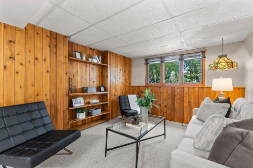 This inviting space features wood-paneled walls, carpeting, built-in shelving, and plenty of natural light.