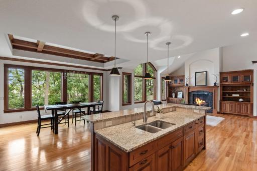 The gourmet custom kitchen showcases stone accents, custom cabinetry, a spacious center island, and seamless connection to the elegant dining and comfortable living areas.
