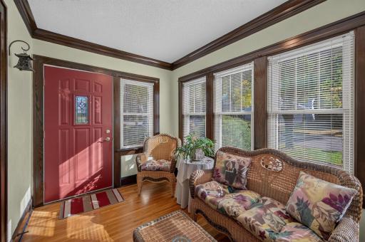 The enclosed porch features windows on three sides, detailed wood trim and a welcoming front entry.