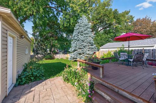 The stamped concrete patio and walkway complement the deck and landscaped backyard.