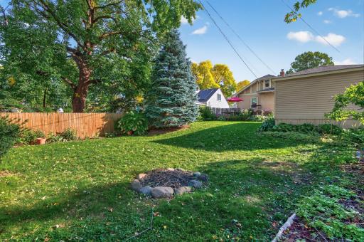 The backyard offers an open lawn, mature shade trees and privacy fencing.