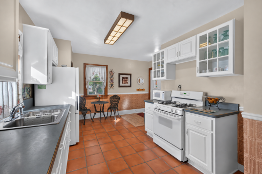 The eat-in kitchen features white cabinetry, glass-front upper cabinets and space for a breakfast table.