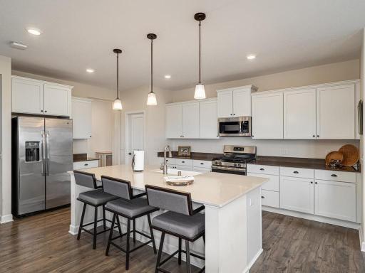 Oversized side by side refrigerator/freezer with ice and filtered water in the door. Gas range! Quartz counters! Plenty of soft closing custom cabinets. LTV premium vinyl plank floor. Walk-in kitchen pantry located behind closed door upper left.