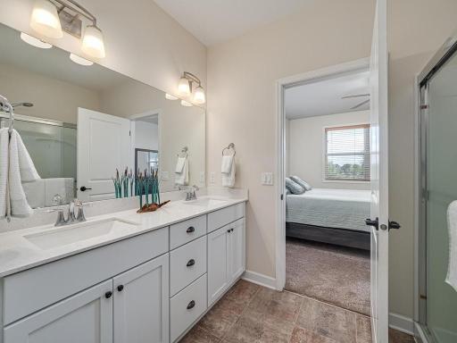 Large vanity with quartz countertop features dual sinks in Owners Suite bathroom.