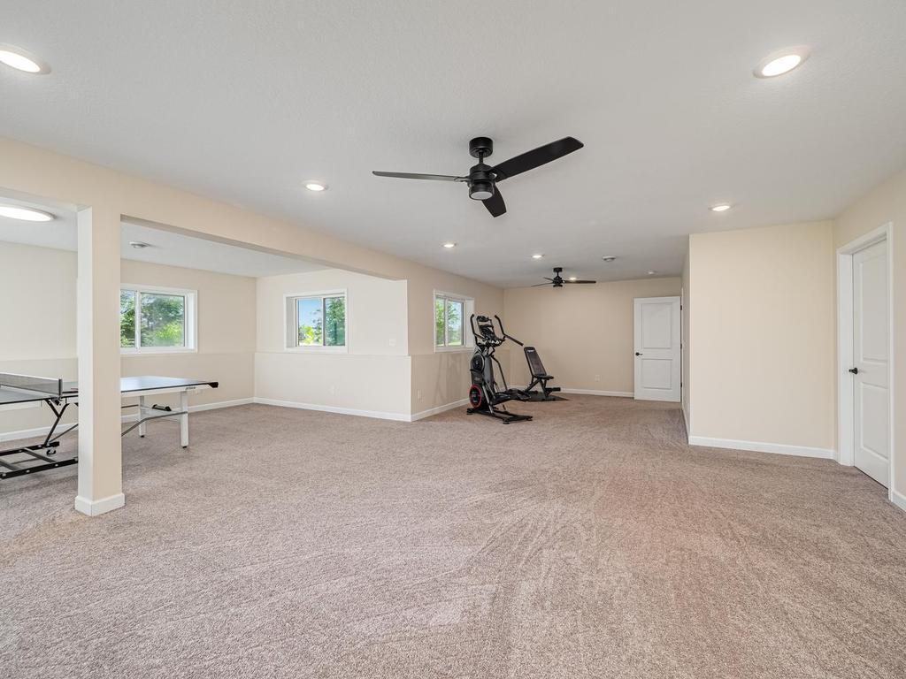 Entrance to the lower level currently used as exercise room. The left side of room used as an amusement room. Sorry ping pong table not included. Ceiling fan with light. Door to the right gives access to large storage room and furnace room.