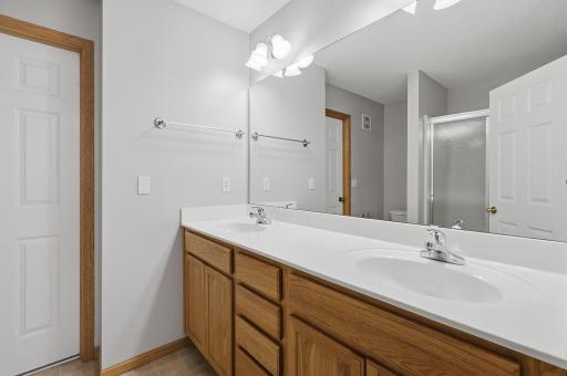The private ensuite features a double-sink vanity with an expansive countertop, ample cabinetry and a large wall mirror, giving two people plenty of room to get ready.