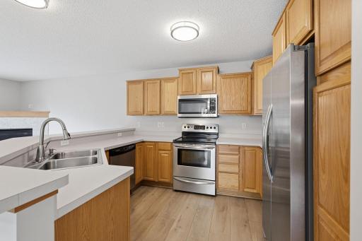 A full suite of stainless steel appliances complements the warm wood cabinetry, with generous counter space and abundant storage, including a pantry with convenient pull-out drawers for easy access and organization.
